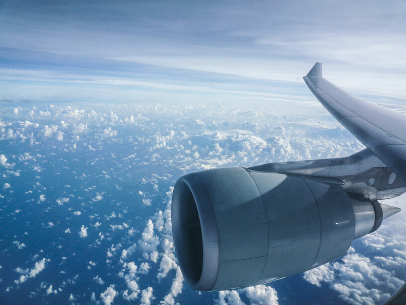 Aircraft engine and wing flying over sky full of clouds